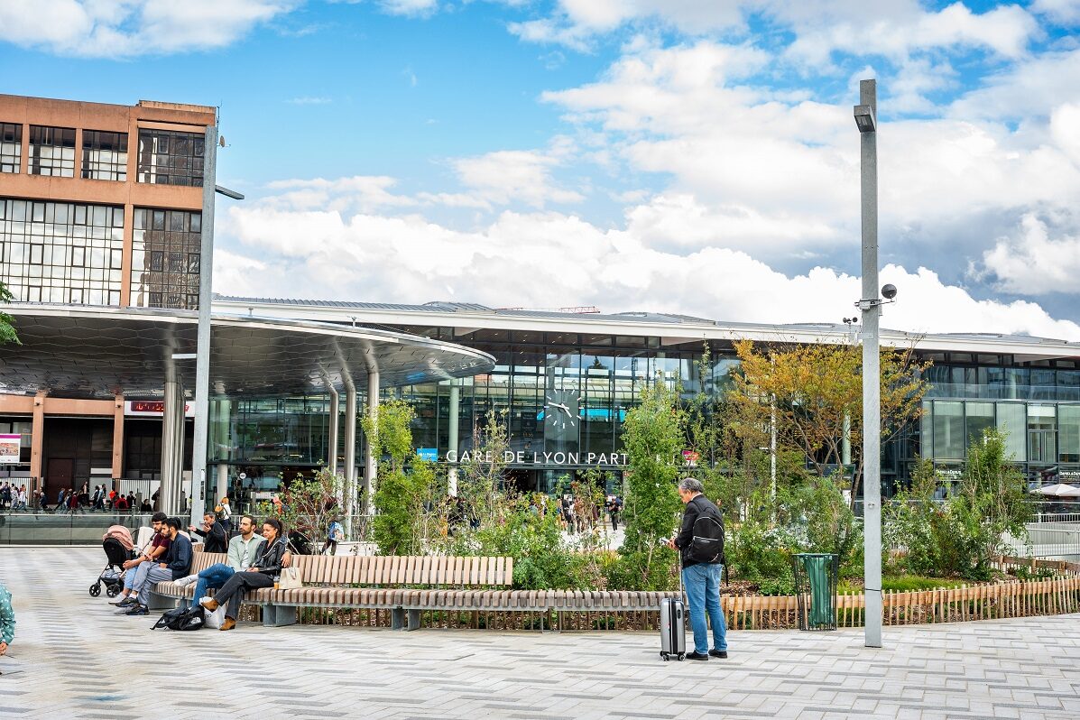Gare moderne avec voyageurs devant l'entrée principale.