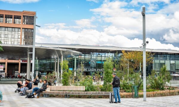 Gare moderne avec voyageurs devant l'entrée principale.