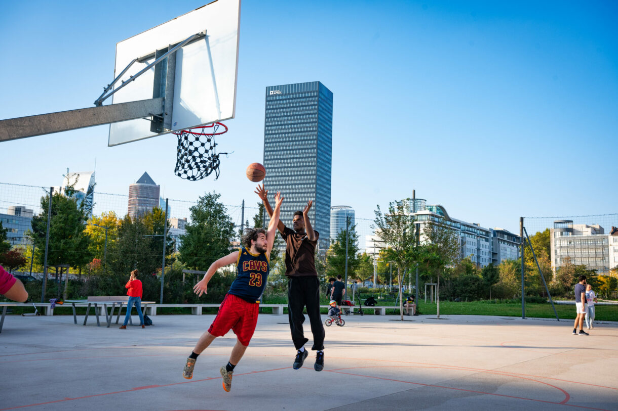 Match de basketball en plein air, deux joueurs sautent.