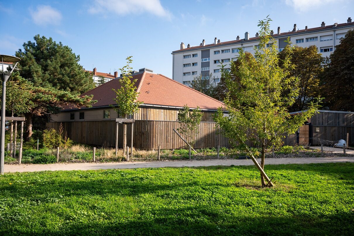 Parc végétalisé, arbres et pelouses verdoyantes, bâtiment en bois