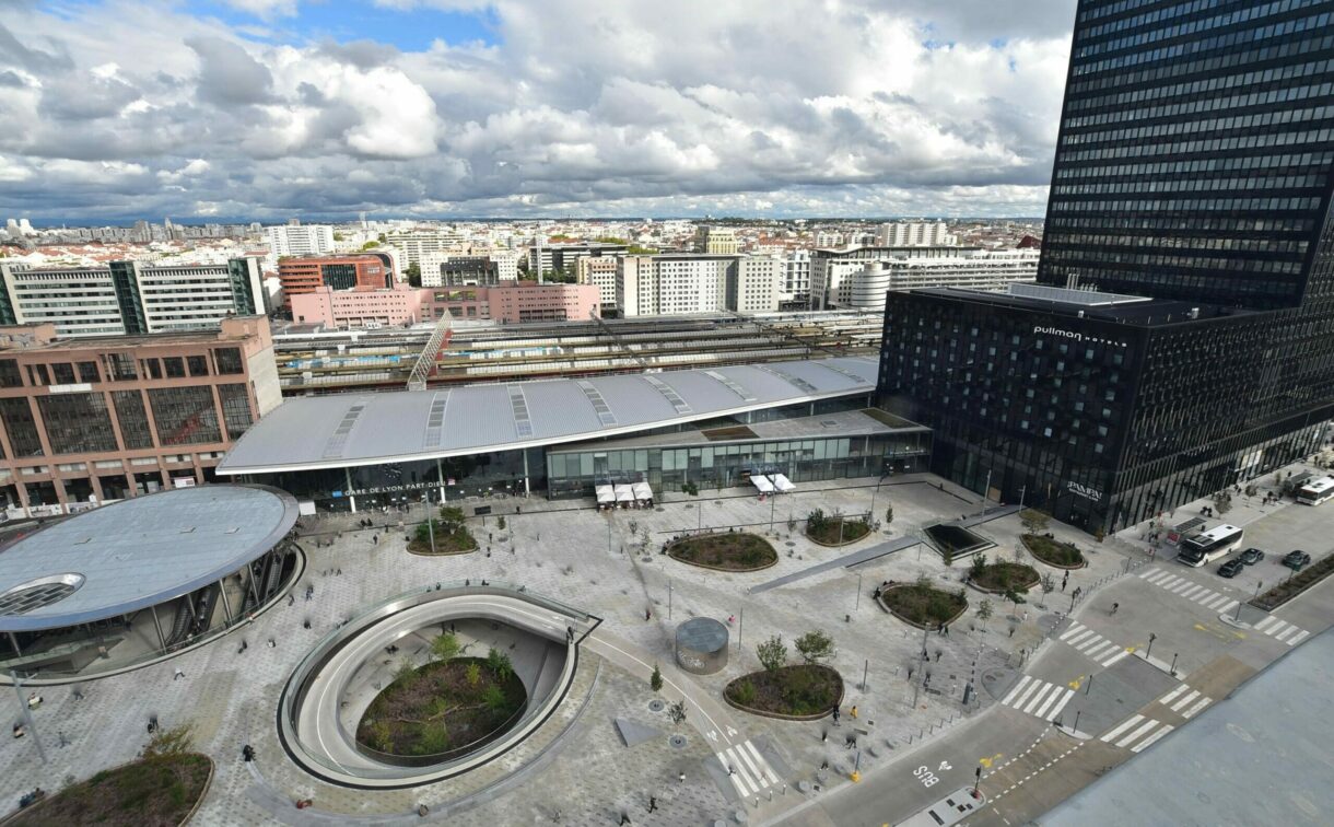 Vue aérienne d'une gare avec immeubles environnants.