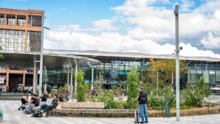 Gare de Lyon Part-Dieu avec voyageurs et verdure.