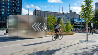 Cycliste devant un parking à vélos moderne en ville.