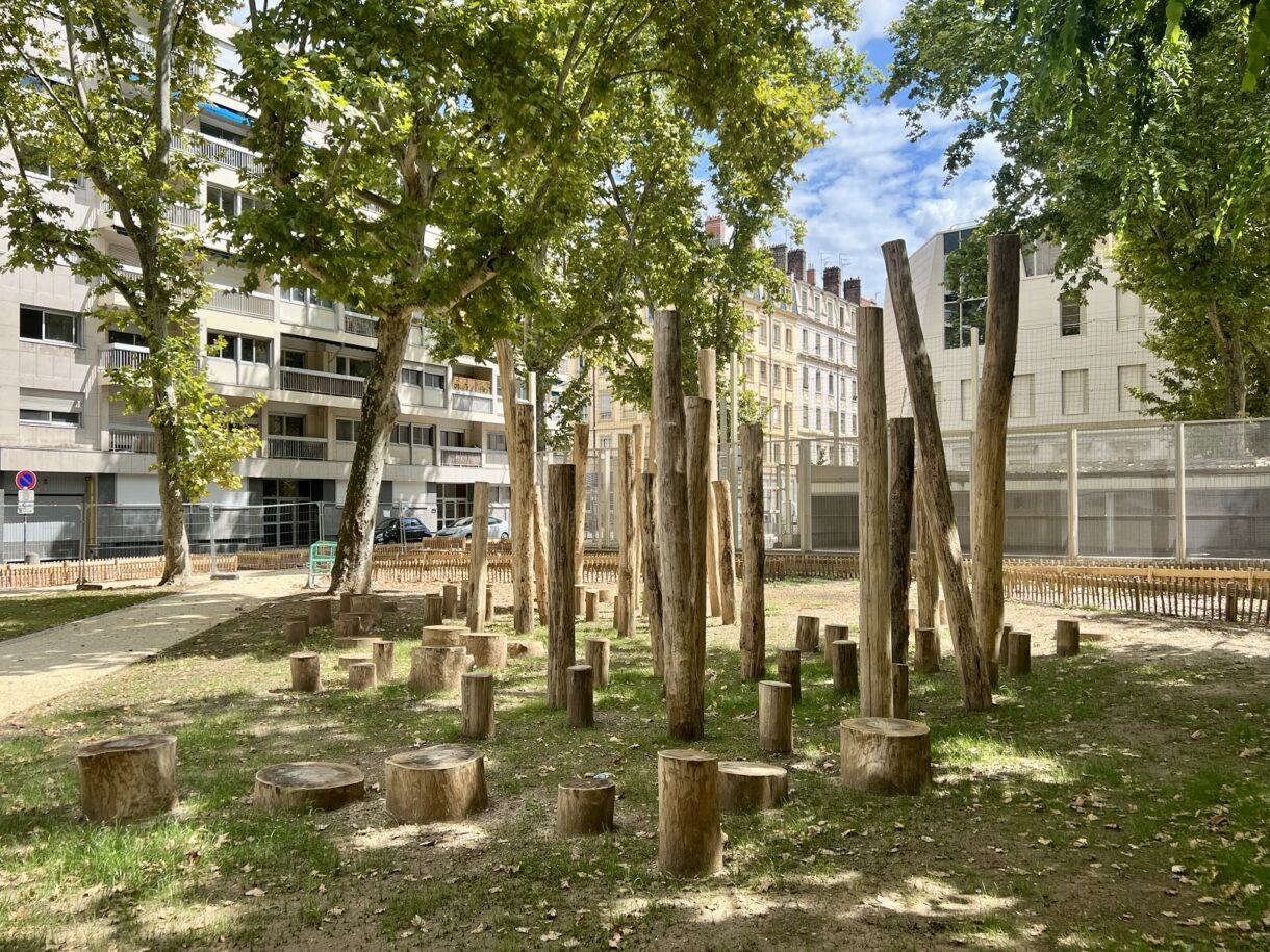 Jeux en rondins dans parc urbain ombragé.