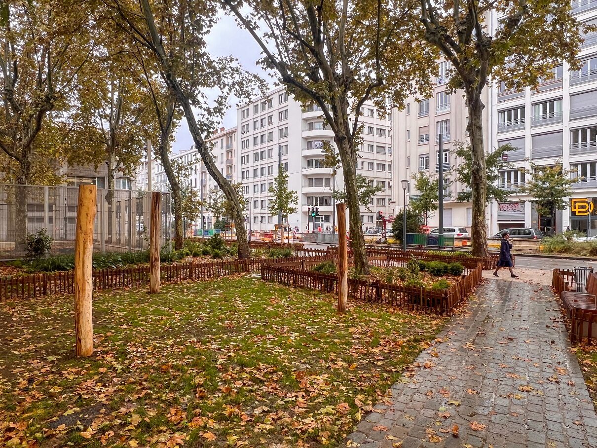 Parc urbain en automne avec bâtiments en arrière-plan.