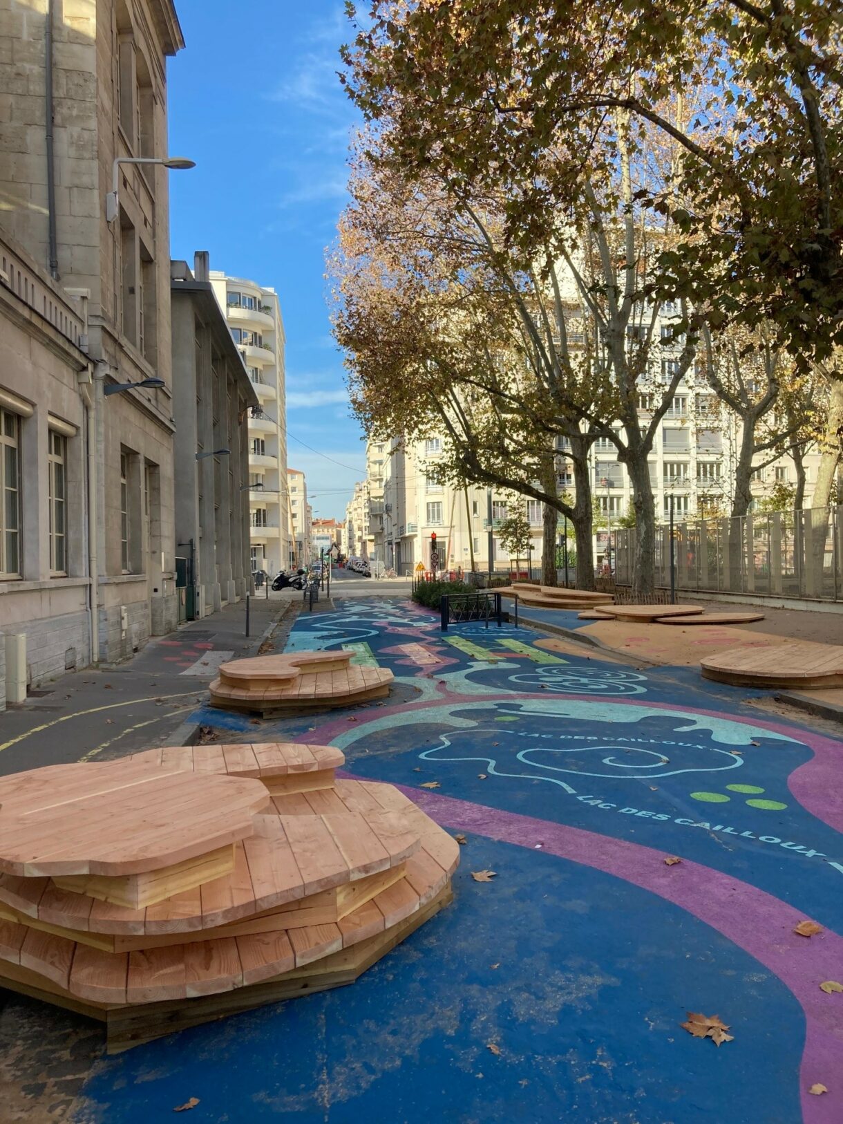Rue colorée avec bancs en bois, arbres automnaux.